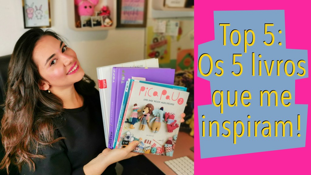 Mulher segurando 5 livros de crochê. Ela veste uma blusa preta, usa batom cor de rosa. O cabelo dela é longo e ela sorri.